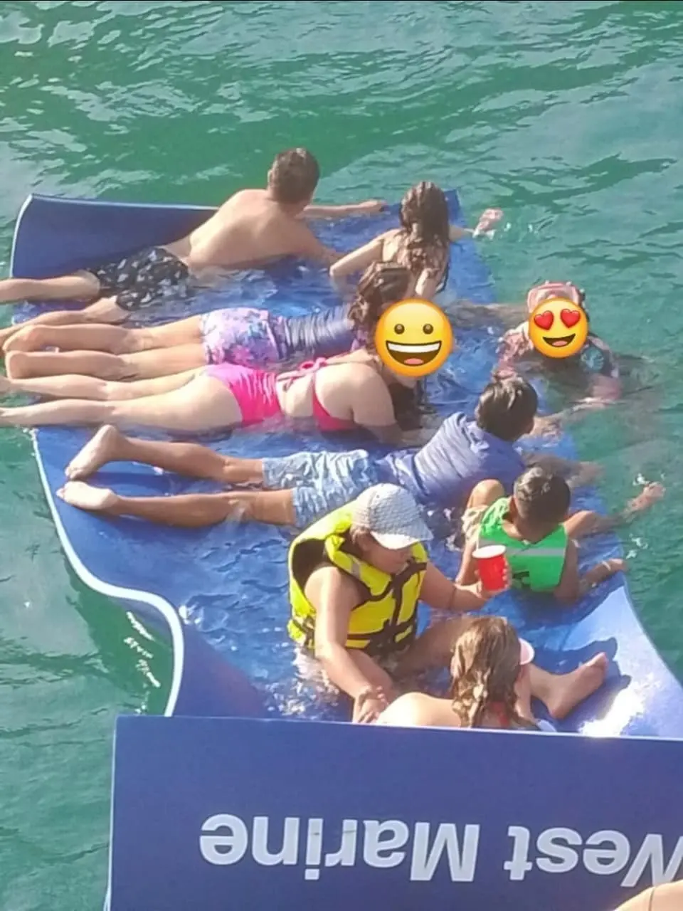 Familia sobre el tapete flotante junto al yate