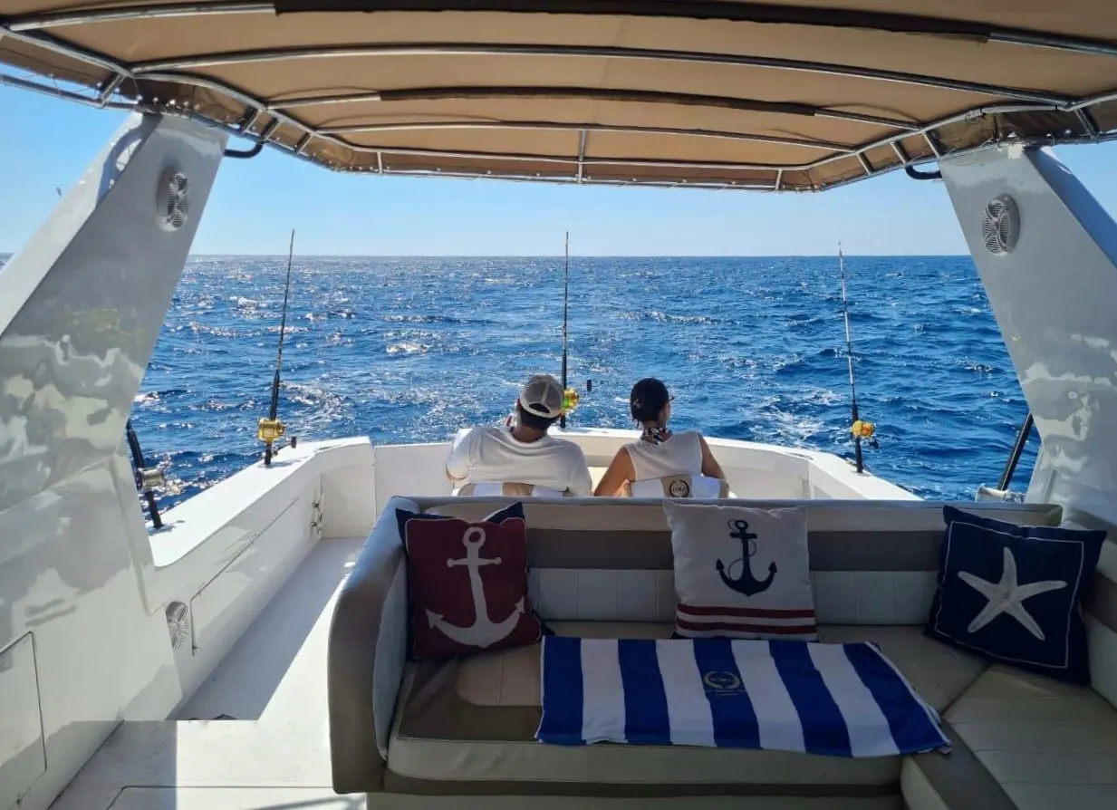 Popa del Toro II con dos pasajeros sentados y cañas de pesca en el mar